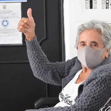 Una paciente adulta mayor levanta el pulgar junto a su acompañante